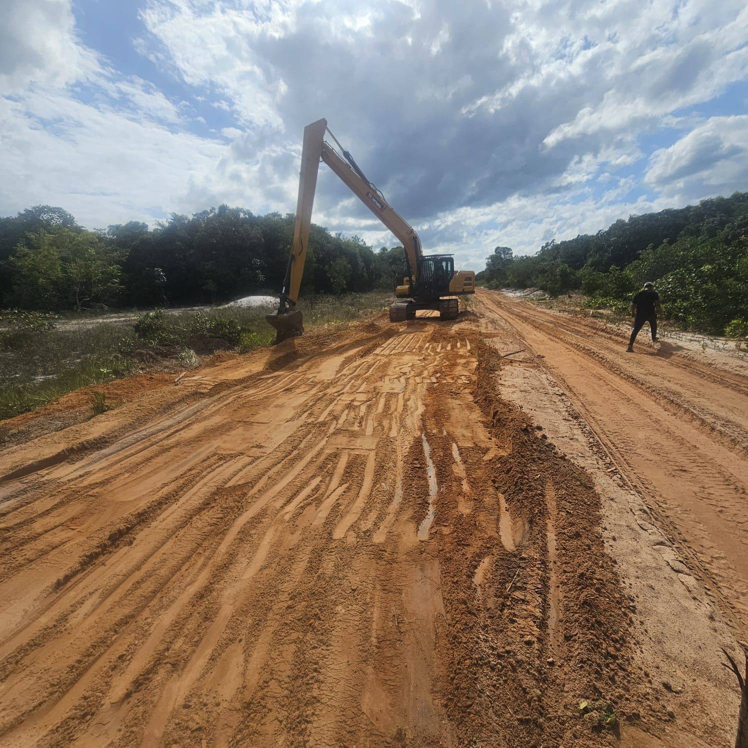 Long-reach excavator shaping a road embankment