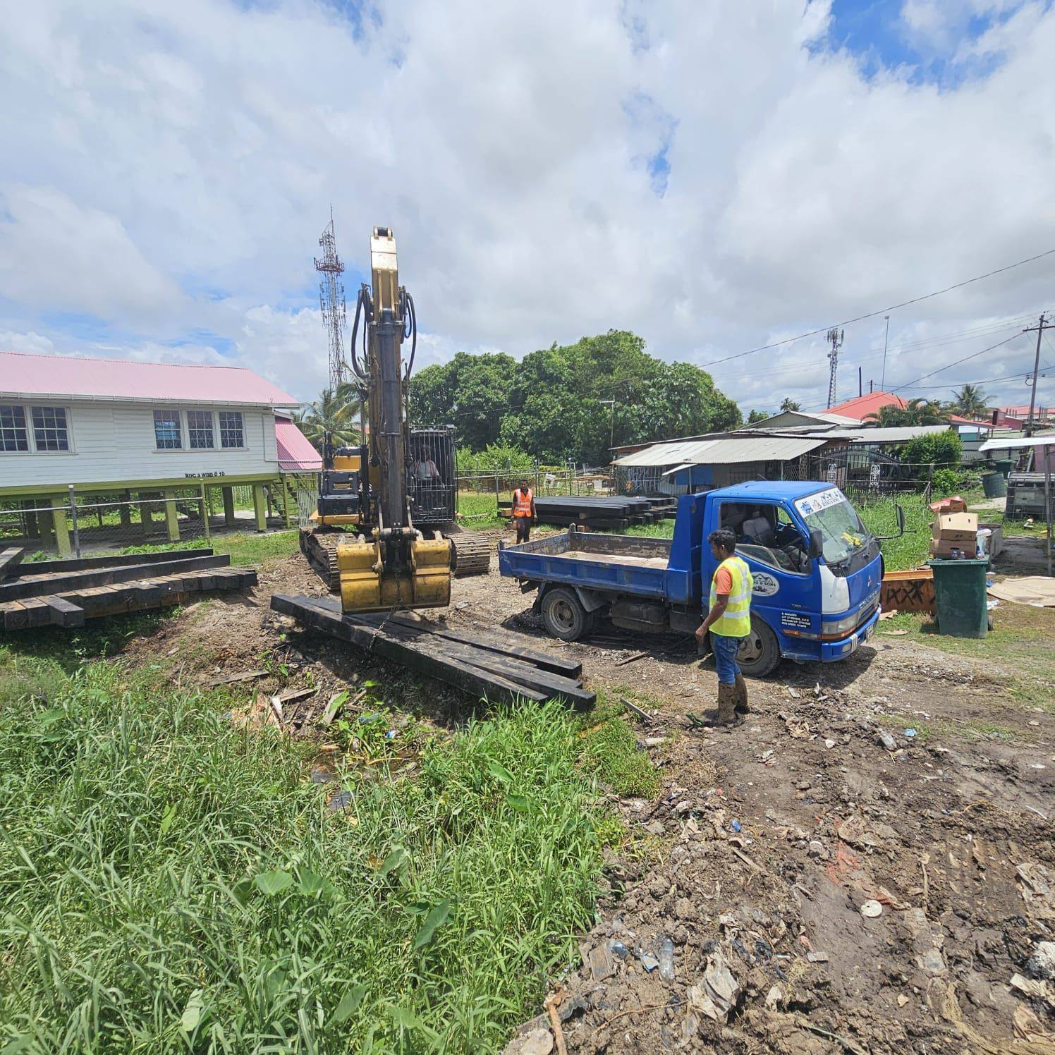 Zeebo & Sons excavator-mounted pile driver on site beside timber and sheet piles