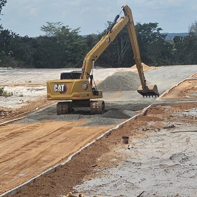 Excavator spreading stone between kerbs on a new road